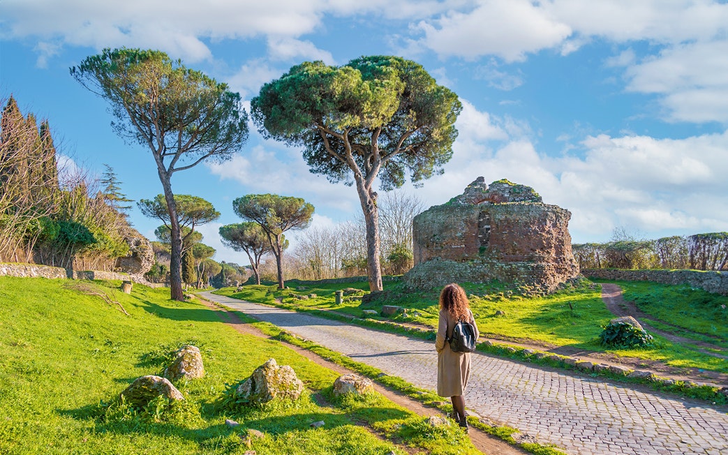 Walking along the Appian Way near ancient ruins and trees, Rome.