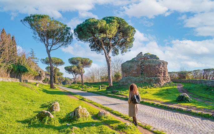 Walking along the Appian Way near ancient ruins and trees, Rome.
