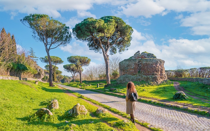 Walking along the Appian Way near ancient ruins and trees, Rome.