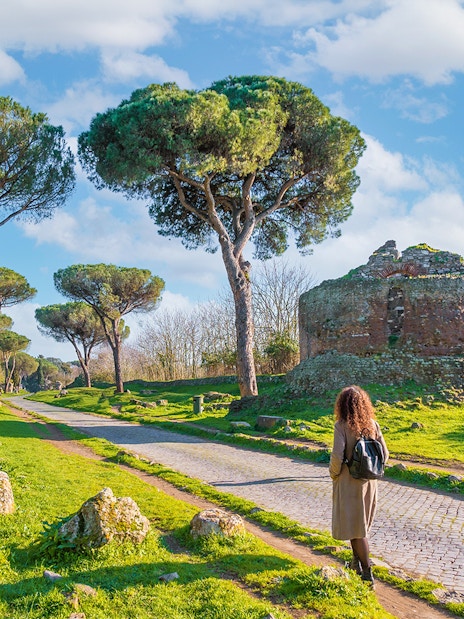 Walking along the Appian Way near ancient ruins and trees, Rome.
