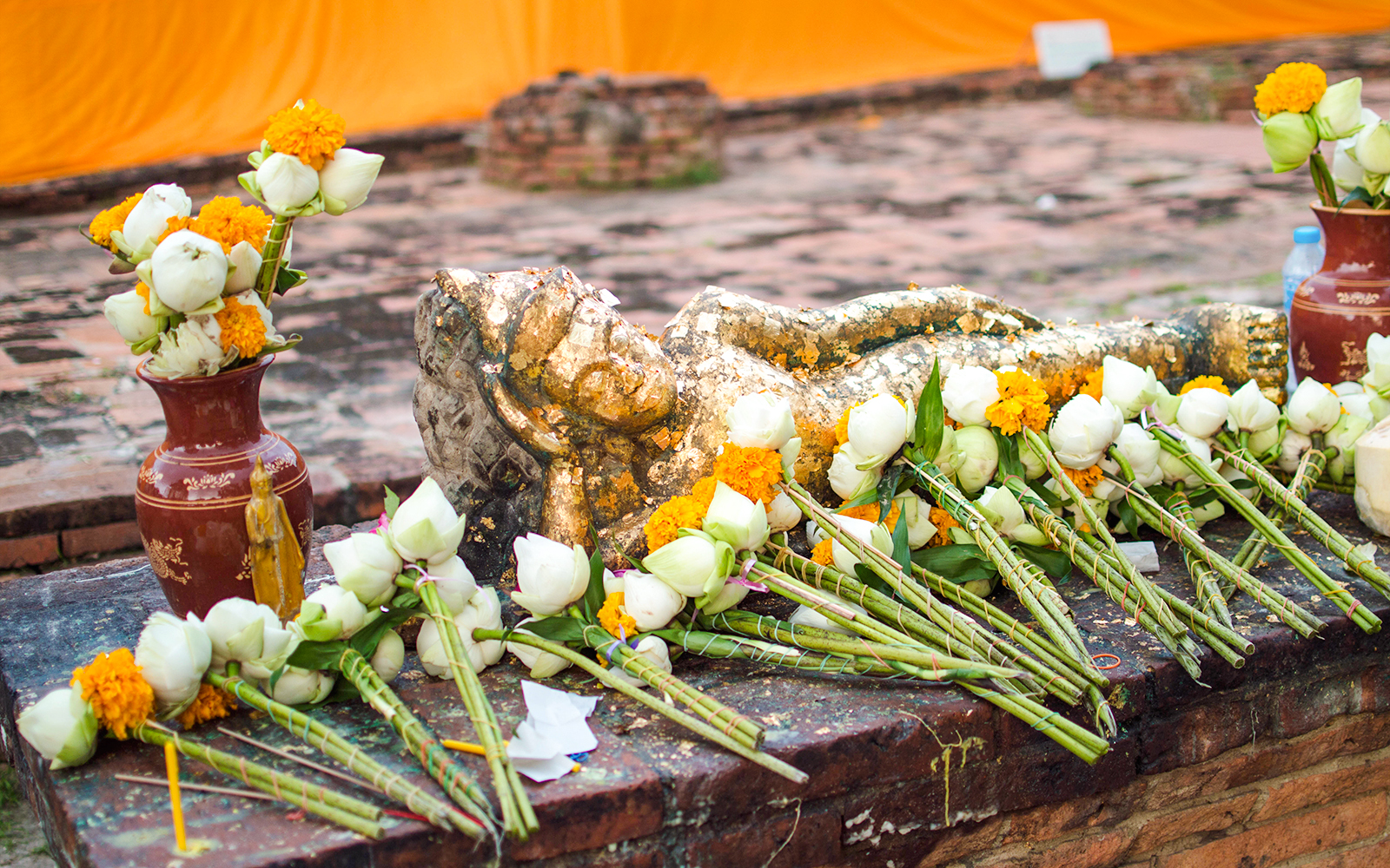 Reclining Buddha statue with flowers at Wat Lokayasutharam, Ayutthaya.