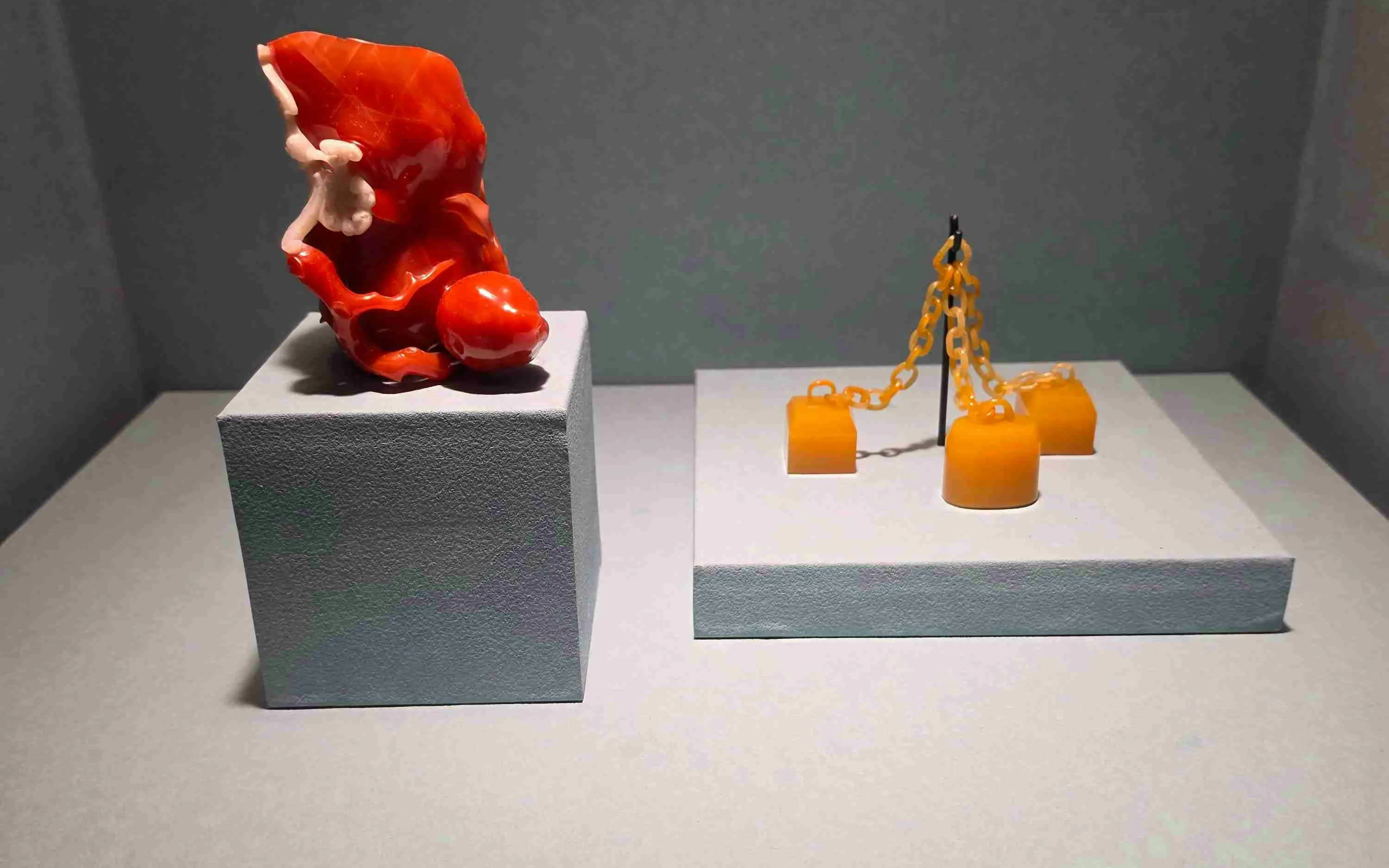 Exhibit of red coral sculpture and yellow chain artifact at National Palace Museum.
