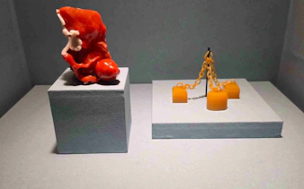 Exhibit of red coral sculpture and yellow chain artifact at National Palace Museum.