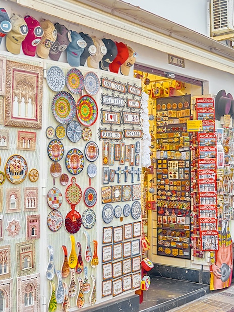 Handicraft store displays colorful ceramics and souvenirs on Calle Deanes, Cordoba, Spain.