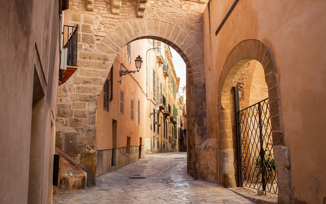 Old stone archway and narrow street in Palma de Mallorca.