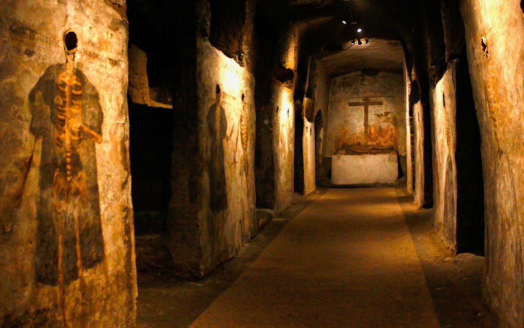 Visitors touring the Catacombs of San Gaudioso, Naples, Italy, with ancient frescoes.