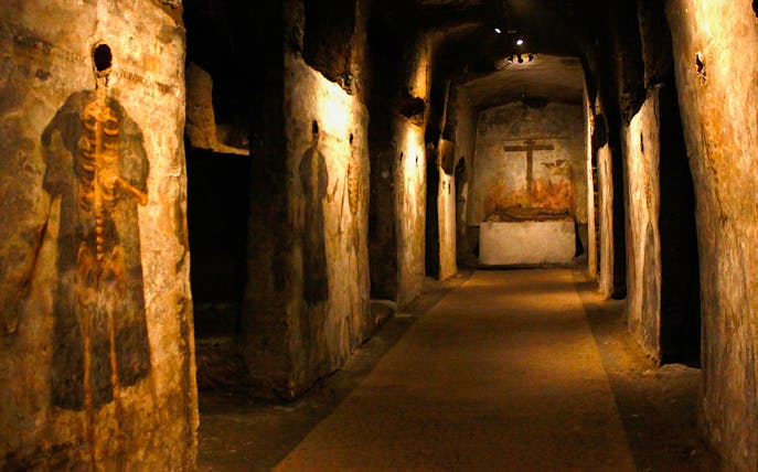 Visitors touring the Catacombs of San Gaudioso, Naples, Italy, with ancient frescoes.