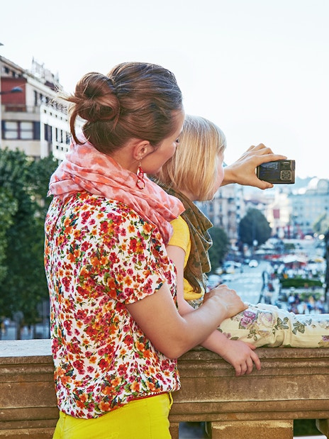 Mother and child taking a selfie near Prague National Museum with city view.