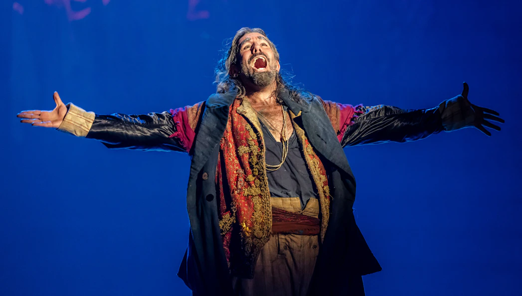 Performer in costume on stage during Oliver production.