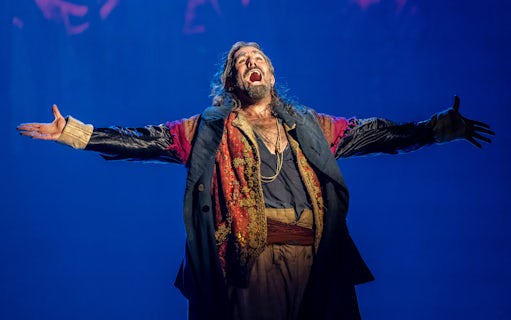 Performer in costume on stage during Oliver production.
