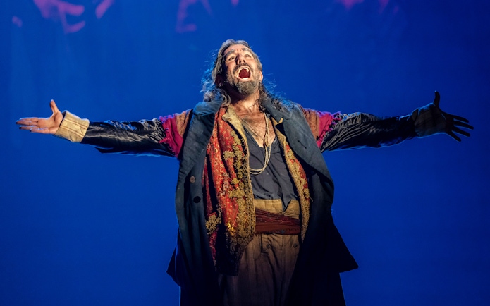 Performer in costume on stage during Oliver production.