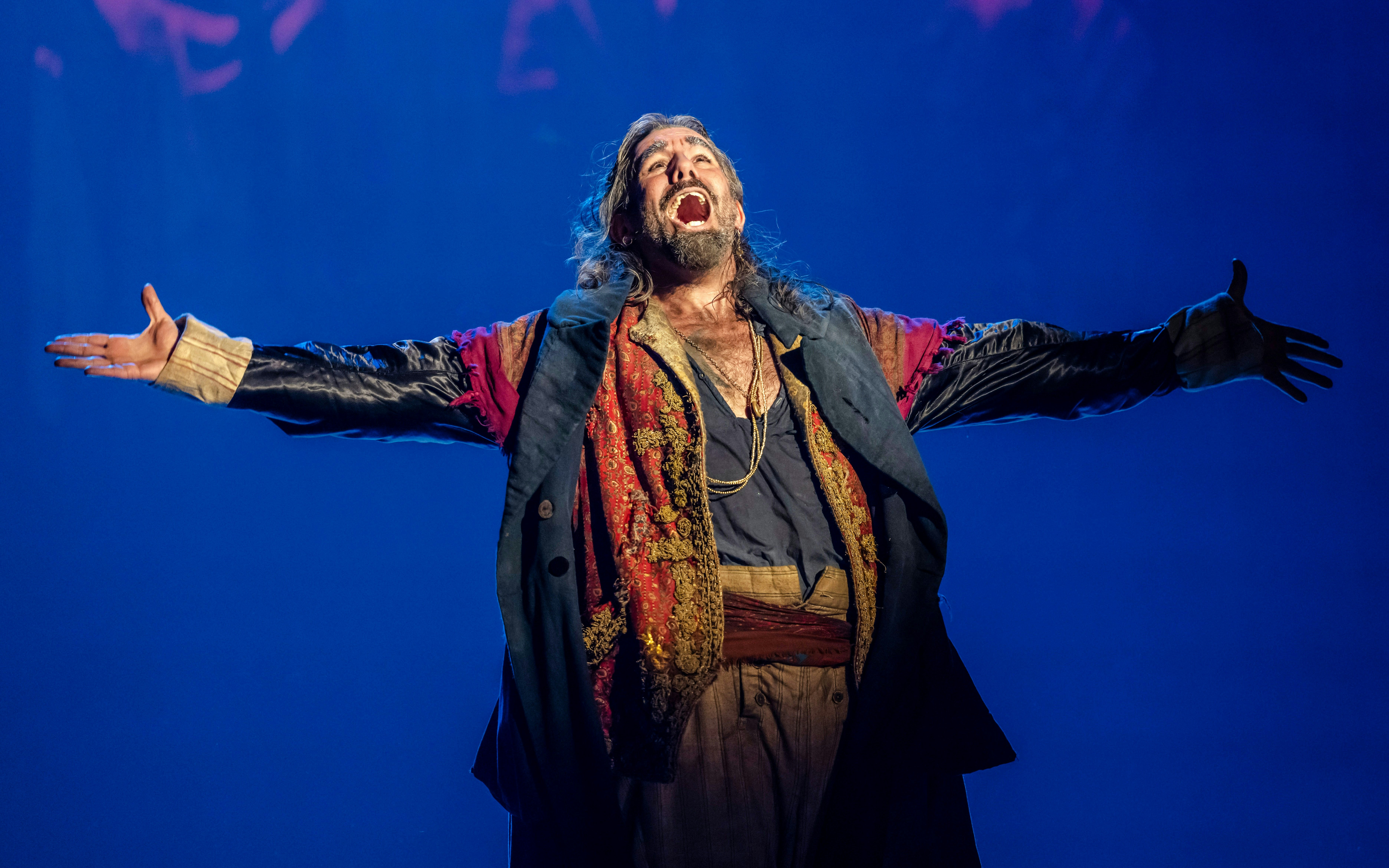 Performer in costume on stage during Oliver production.