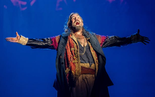 Performer in costume on stage during Oliver production.