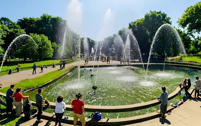 Fountains at Versailles Gardens with tourists on a guided golf cart and bike tour.