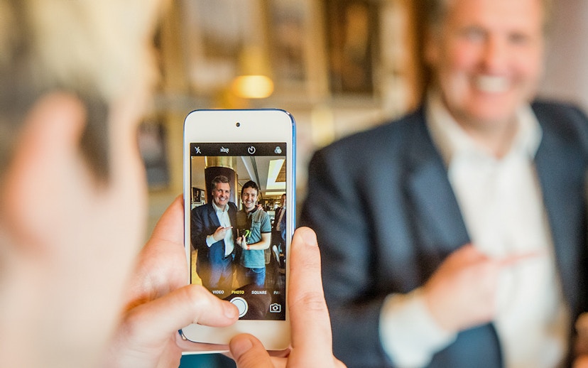 Person taking a photo of two people smiling during Liverpool FC Legends Q&A and Stadium Tour.