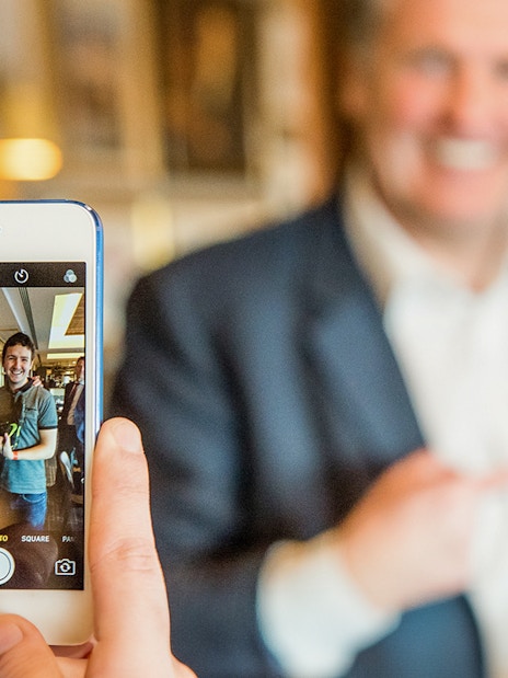 Person taking a photo of two people smiling during Liverpool FC Legends Q&A and Stadium Tour.