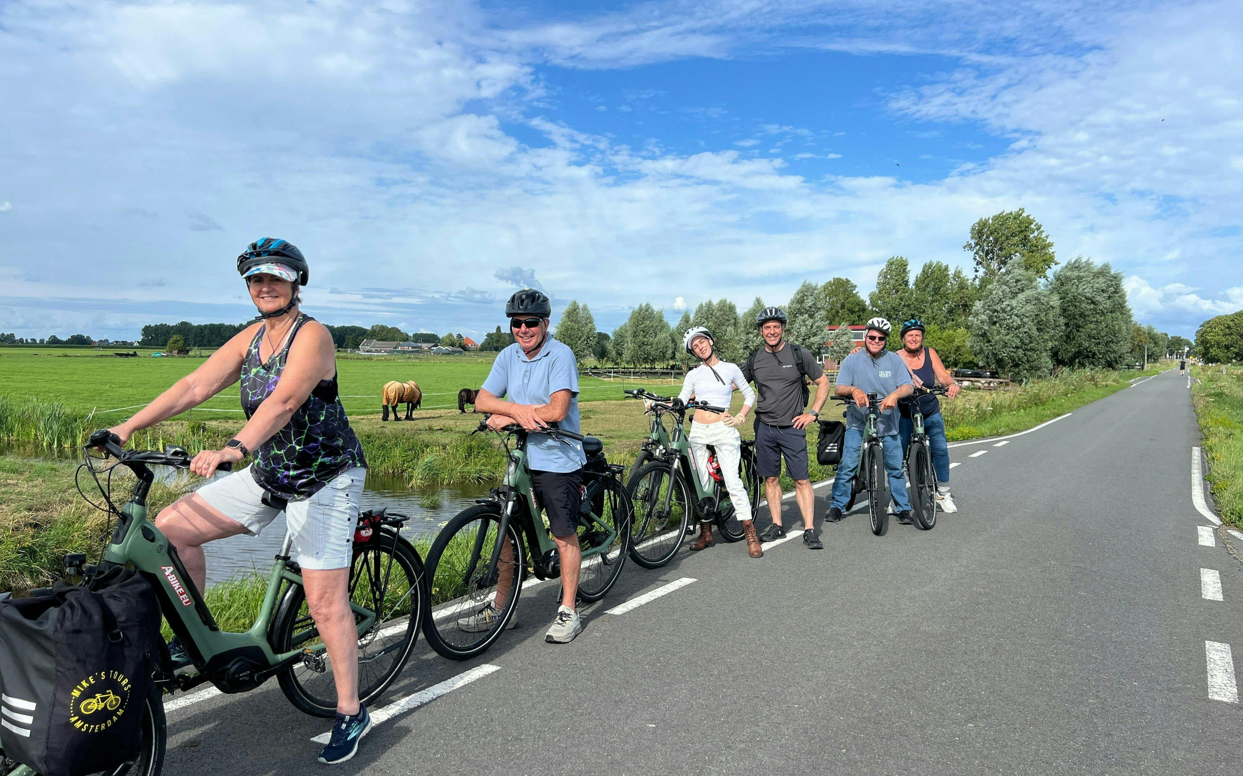 Group on e-bike tour in Dutch countryside with fields and horses.