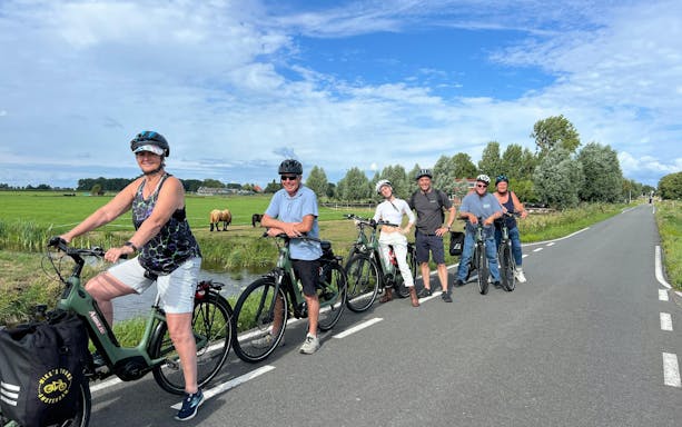 Group on e-bike tour in Dutch countryside with fields and horses.