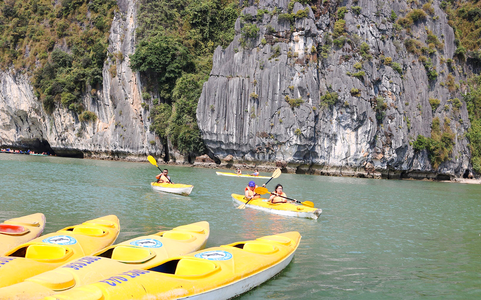 Kayakers paddling in Ha Long Bay near rocky islands.