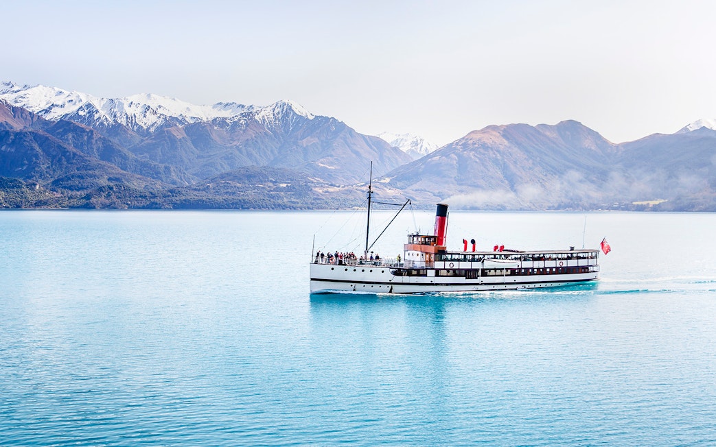 Steamboat cruising on Lake Wakatipu with snow-capped mountains in the background.
