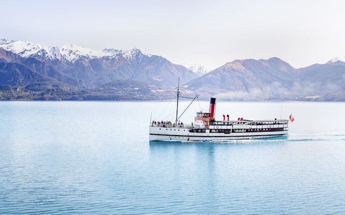 Steamboat cruising on Lake Wakatipu with snow-capped mountains in the background.