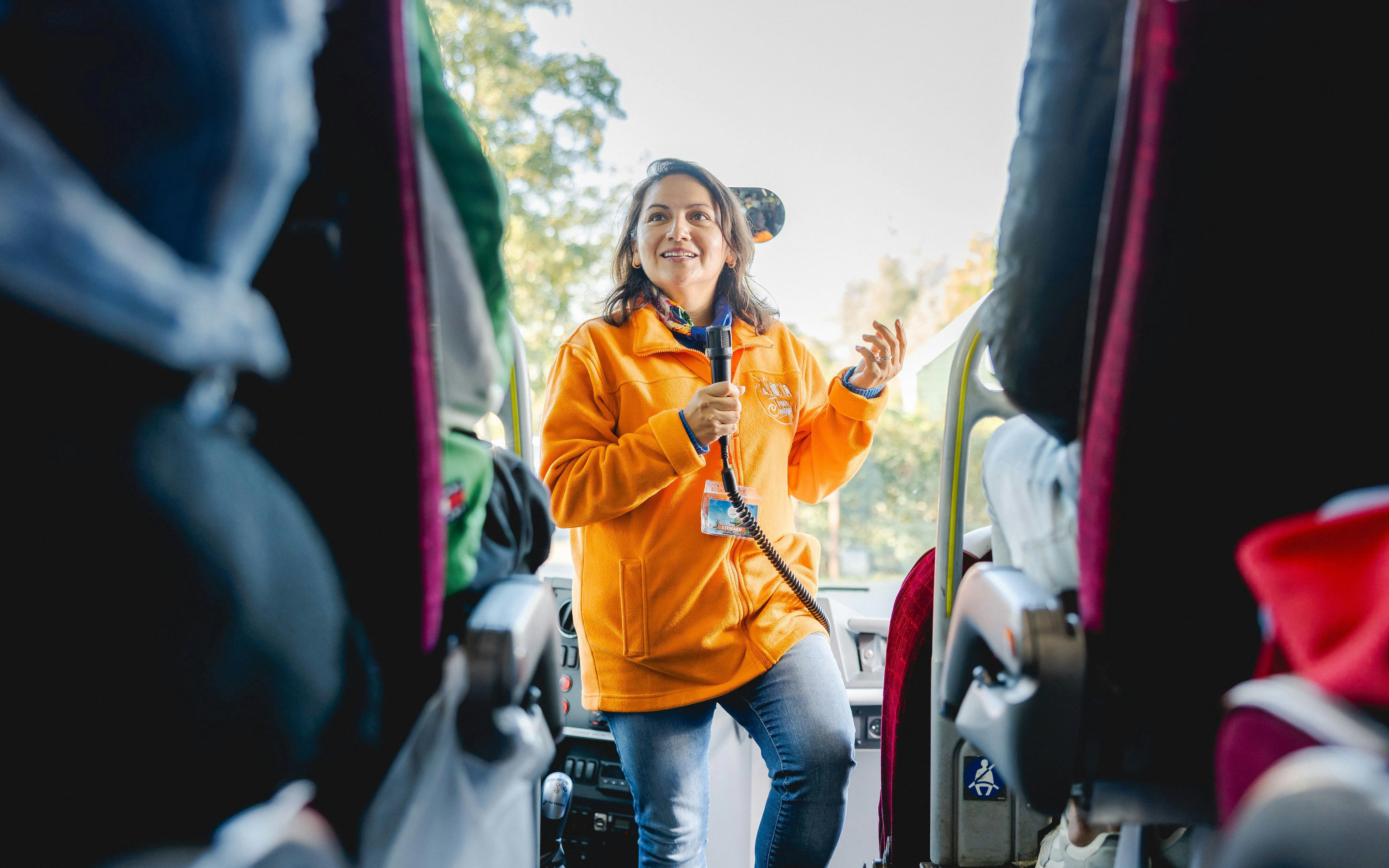 Tour guide speaking to passengers on a bus tour.