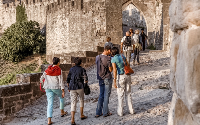 Tourists walking through the stone pathway of Carcassonne Castle.