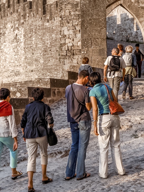 Tourists walking through the stone pathway of Carcassonne Castle.