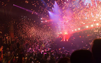 Confetti shower at a lively concert party with vibrant stage lights.