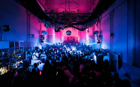 Crowded nightclub with vibrant lighting and a disco ball at SUPPERCLUB Amsterdam.