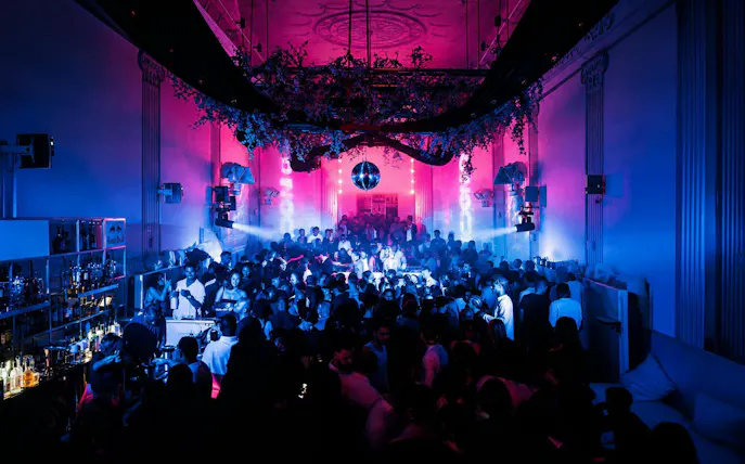 Crowded nightclub with vibrant lighting and a disco ball at SUPPERCLUB Amsterdam.