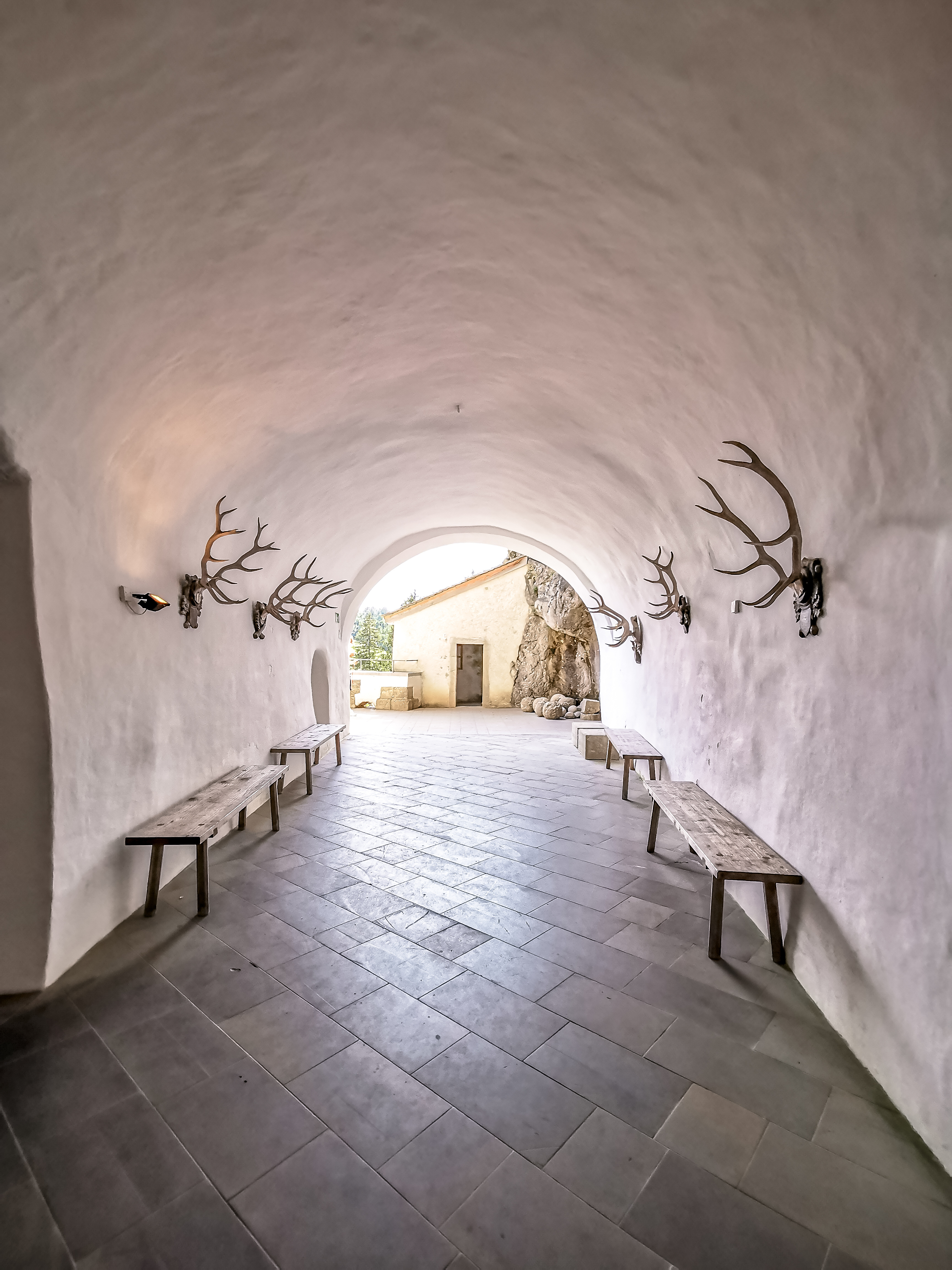 Interior corridor of Predjama Castle with antlers on walls and stone benches.