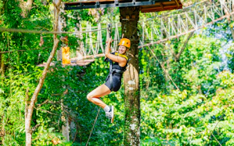 Person ziplining through lush forest at Sky Rock Zipline Adventure, Khao Lak.