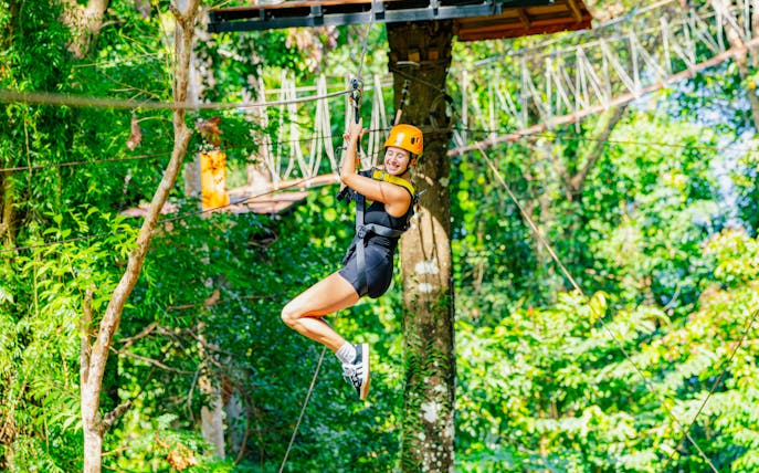 Person ziplining through lush forest at Sky Rock Zipline Adventure, Khao Lak.