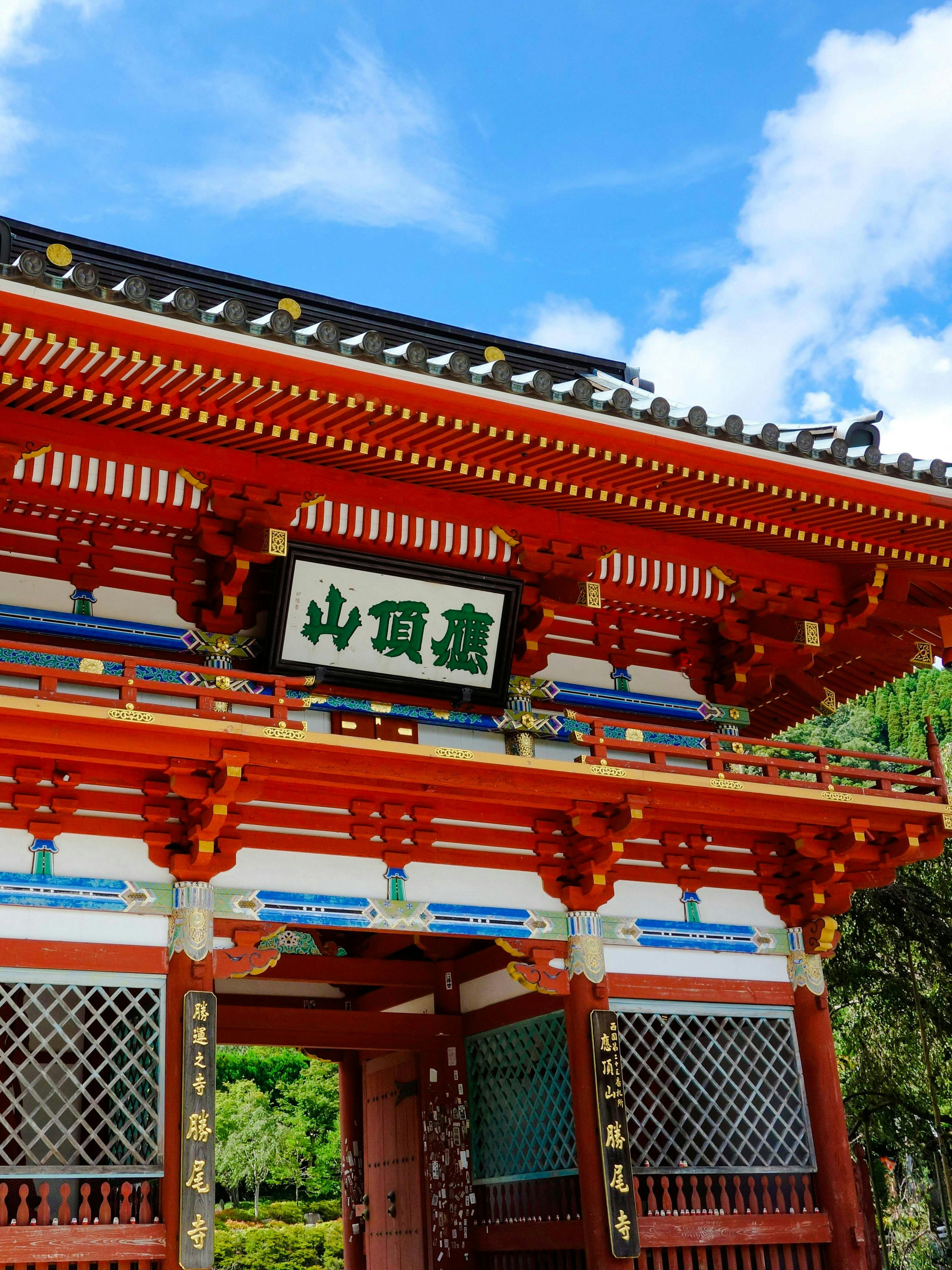 Katsuo Ji Temple entrance gate with traditional red and white architecture surrounded by greenery.