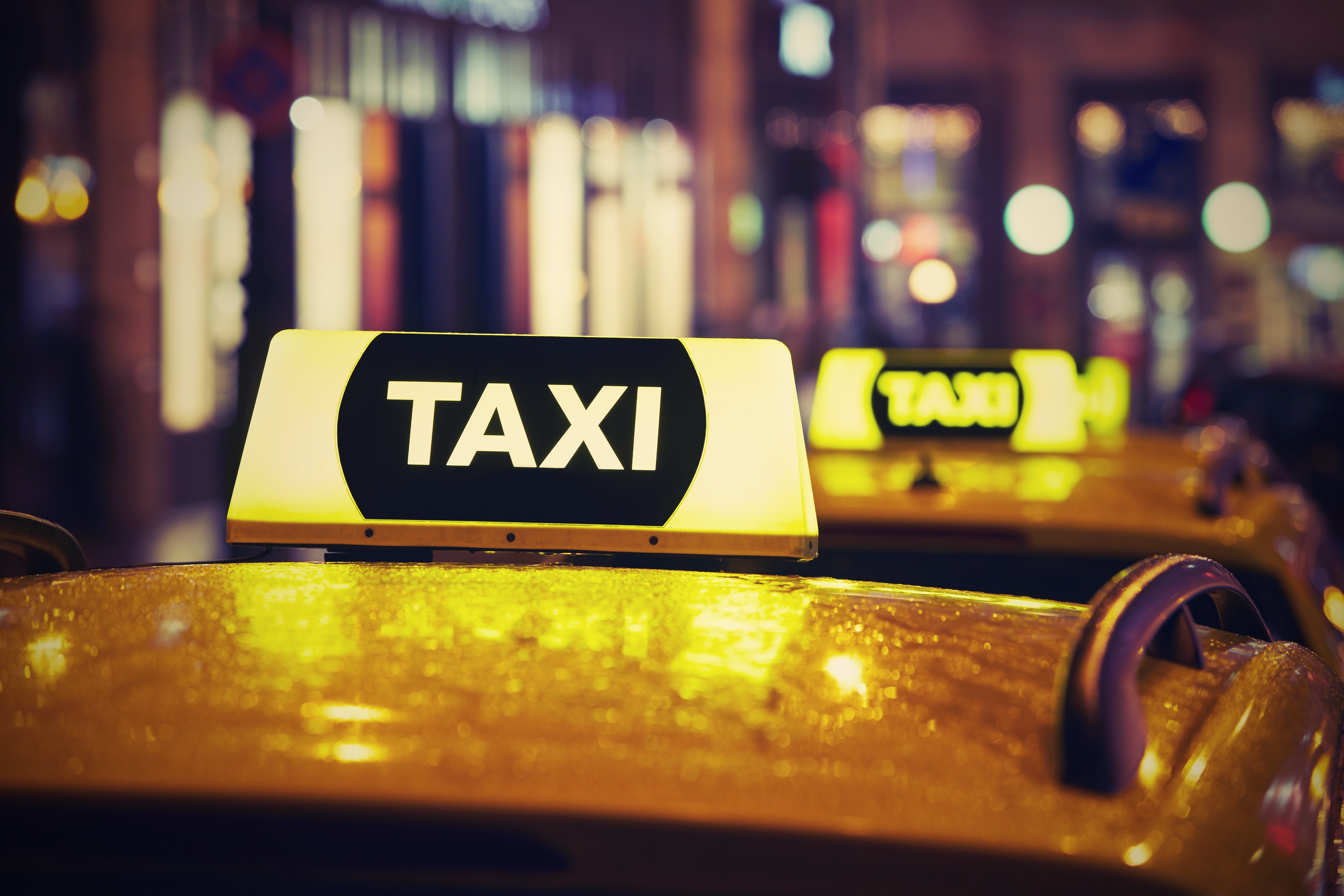 Taxi with illuminated sign at night in city.