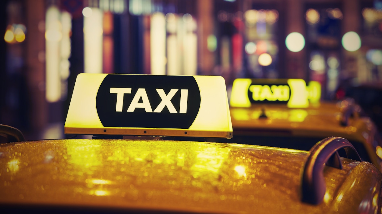 Taxi with illuminated sign at night in city.