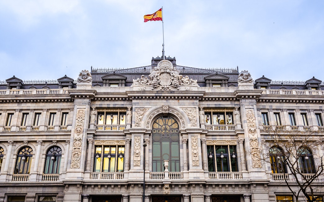 Bank of Spain building facade with Spanish flag in Madrid.