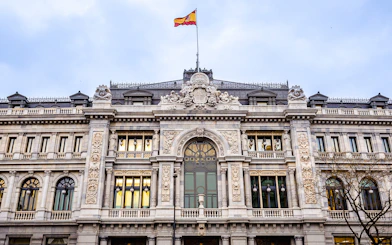 Bank of Spain building facade with Spanish flag in Madrid.