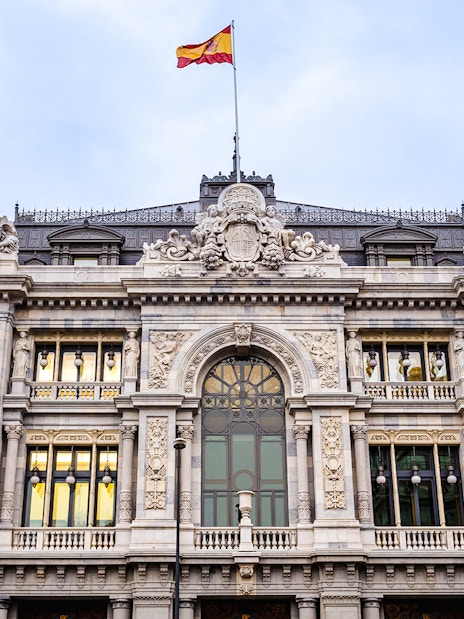 Bank of Spain building facade with Spanish flag in Madrid.