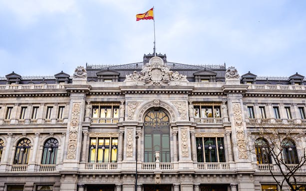 Bank of Spain building facade with Spanish flag in Madrid.