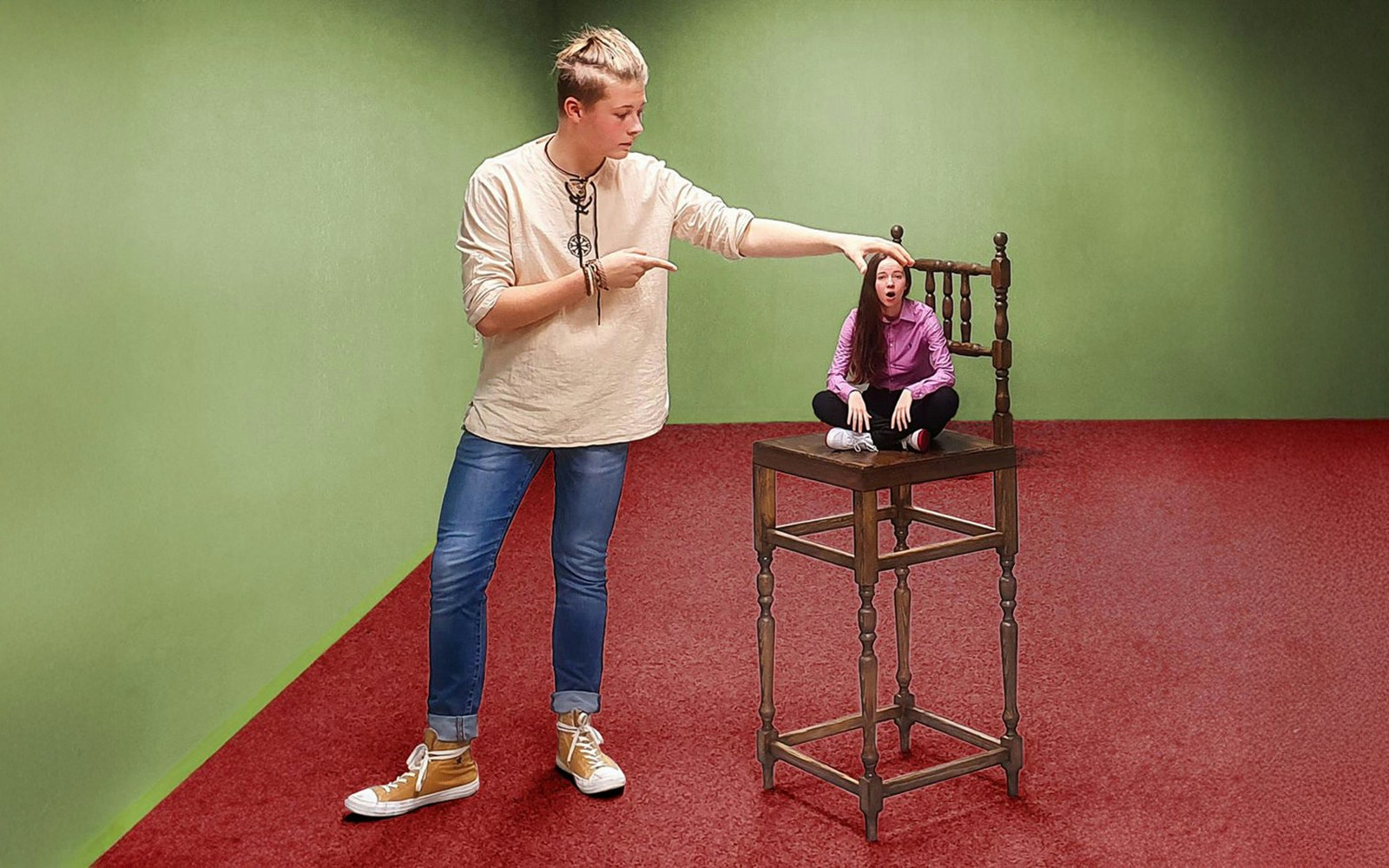 Person interacting with Magic Chair illusion in Museum of Fantastic Illusions.