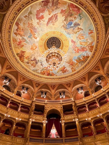 Hungarian State Opera House interior with ornate ceiling fresco and chandelier.