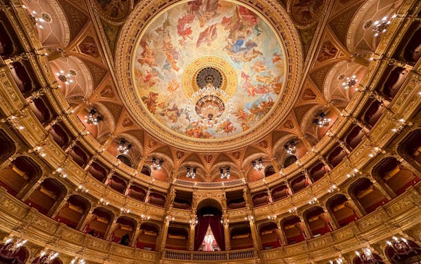 Hungarian State Opera House interior with ornate ceiling fresco and chandelier.