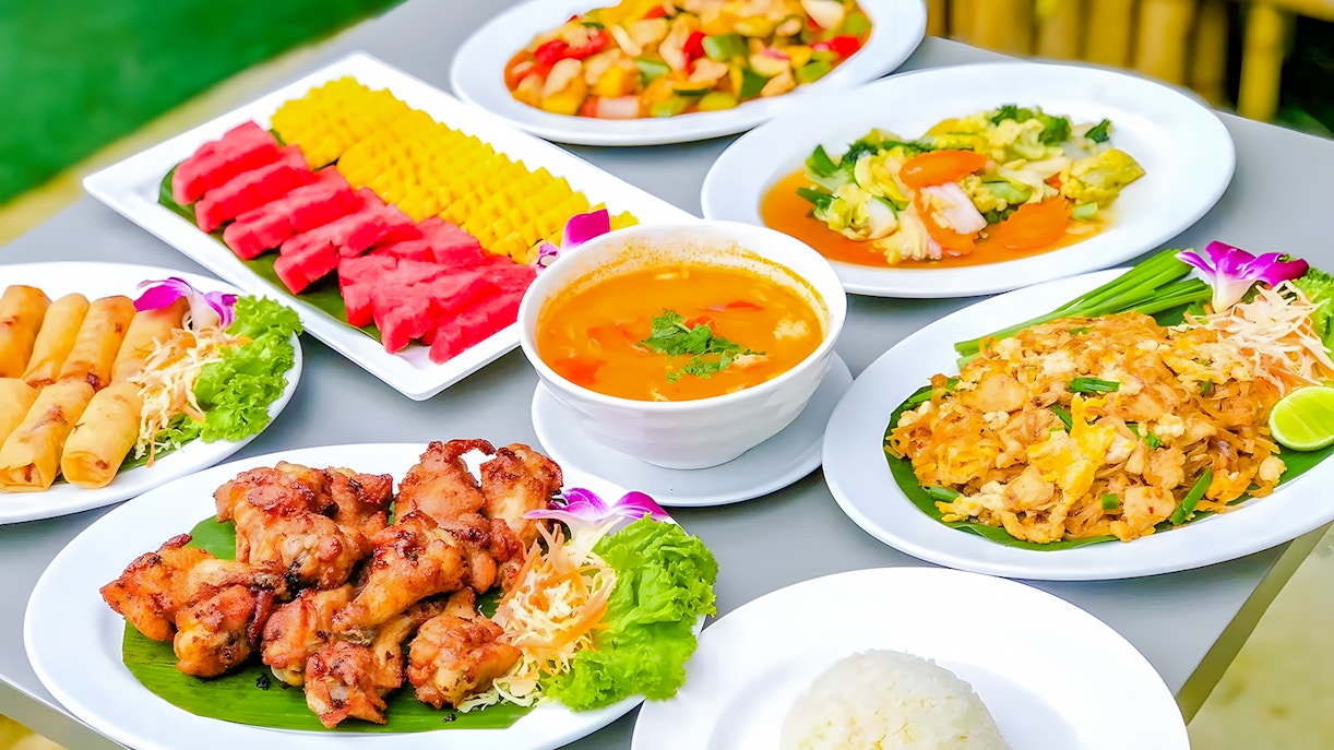 Thai buffet lunch with spring rolls, grilled chicken, curry, and fruit in Phuket Elephant Care.