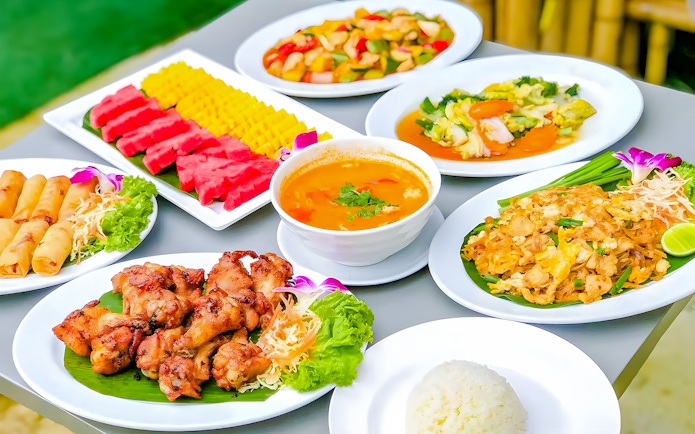 Thai buffet lunch with spring rolls, grilled chicken, curry, and fruit in Phuket Elephant Care.