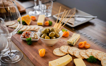 Cheese and olive platter with wine glasses on a Queenstown wine tour.