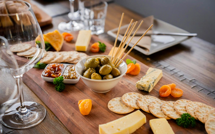 Cheese and olive platter with wine glasses on a Queenstown wine tour.
