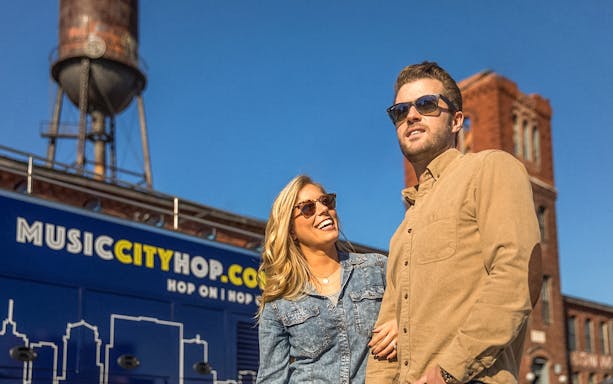 Couple enjoying Music City Hop tour in Nashville with historic buildings in background.
