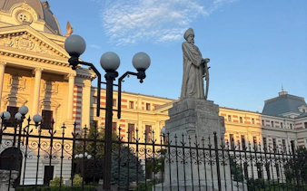 Statue and historic building in Bucharest during self-guided city exploration game.